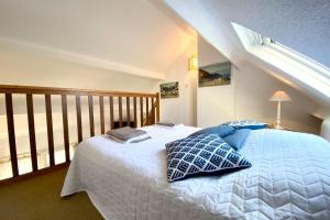 - une chambre avec un lit blanc et des oreillers bleus dans l'établissement Maisonnette de charme Bord de mer Piscine, à Guidel