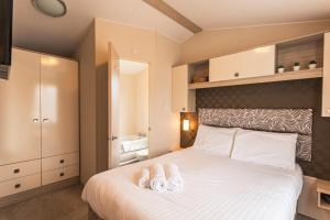 a bedroom with a bed with two towels on it at Meadows Lodge with Hot Tub in Malton