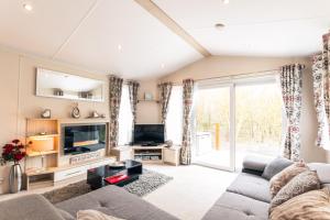 a living room with a couch and a tv at Meadows Lodge with Hot Tub in Malton