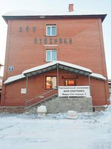 un bâtiment en briques rouges avec un panneau devant lui dans l'établissement Hunter's Hut, à Novossibirsk