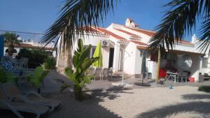 Biały dom z krzesłami i palmą w obiekcie VILLA DOS-LAGOS w mieście Torrevieja