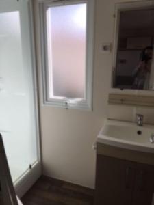 bagno con lavandino e finestra di CAMPING LE MARINE a Le Grau-du-Roi