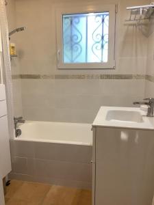 ein Badezimmer mit Badewanne und Waschbecken und einem Fenster in der Unterkunft Maison 4 adultes et 4 enfants - 250m de la plage in La Guérinière + 26 Fotos