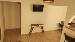 Habitación con mesa y TV en la pared. en Casa Temporada Castelinho Campinas, en Campinas