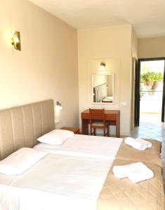 a bedroom with two beds and a desk and a mirror at Oasis Beach Club in Kavos
