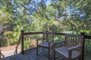 eine Holzbank auf einer mit Bäumen bewachsenen Terrasse in der Unterkunft Green Winged Teal in Kiawah Island