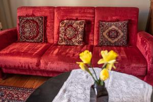a red couch with pillows and a table with yellow flowers at Hostel, Pokoje gościnne Mleczarnia - Ozonowane in Wrocław