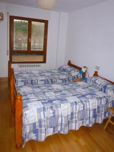 a bedroom with a bed with a blue and white comforter at Apartamentos Formigal - admite mascotas in Formigal