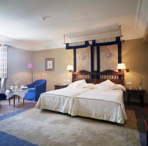 a bedroom with a large bed and a blue chair at Parador de Cuenca in Cuenca +44 photos
