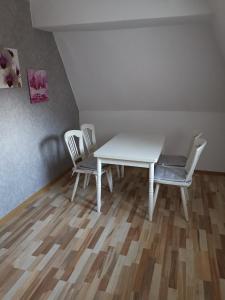 einen weißen Tisch und Stühle in einem Zimmer mit Holzboden in der Unterkunft Ferienwohnung Rote-Villa in Pobershau