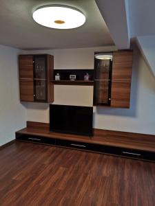 a living room with a flat screen tv and wooden cabinets at Ferienwohnung Rote-Villa in Pobershau