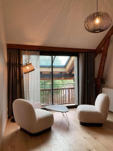 ein Wohnzimmer mit 2 Stühlen, einem Tisch und einem großen Fenster in der Unterkunft Domaine Jacqueline Père & Filles in Aix-les-Bains