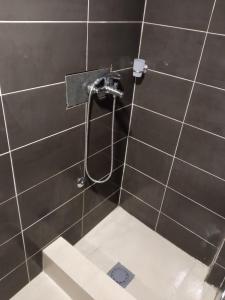 e bagno con doccia su una parete piastrellata di nero. di Monte room a Podgorica