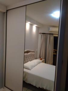 1 dormitorio con cama blanca y espejo en Píer Sul Apart Hotel - Circuito do carnaval, en Salvador