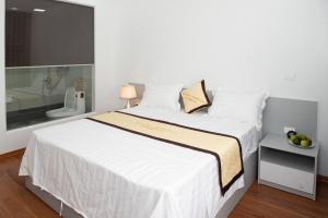 a bedroom with a large white bed and a bathroom at Balanha homestay 1 in Ninh Binh
