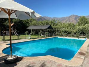 a large blue swimming pool with an umbrella at Paine - Hermosa Parcela de Agrado in Santiago