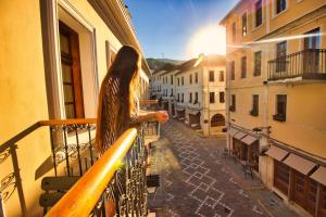 a woman standing on a balcony looking out onto a street at Hotel Argjiro in Gjirokastër