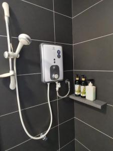 a shower in a black tiled bathroom with a blow dryer at POOLVIEW Geniehome 3BR Free100mbps and Carpark at Utropolis Shah Alam in Shah Alam