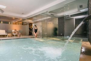 kobieta stojąca w basenie z fontanną w obiekcie Hotel Chalet Del Brenta w Madonna di Campiglio
