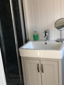 a bathroom with a white sink and a shower at The Shepherd's Hut in Mixbury