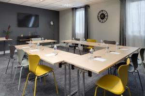 uma sala de conferências com mesas e cadeiras e um relógio em ibis budget Clermont Ferrand Nord Riom em Riom