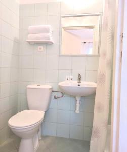 a white bathroom with a toilet and a sink at Pod Różą Economy in Łeba