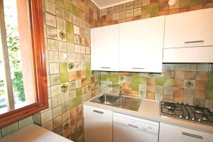 eine Küche mit einem Waschbecken und einer gefliesten Wand in der Unterkunft BA - Maestrale- in Lignano Sabbiadoro
