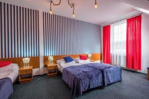 a bedroom with two beds and two windows with red curtains at Przystań Łeba Resort&Restaurant in Łeba