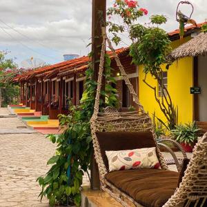 a wicker hammock with plants and a building at Chalé Marinas in Barreirinhas