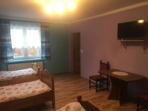 a room with a bed and a table and a tv at Agroturystyka pod świerkami in Giebułtów