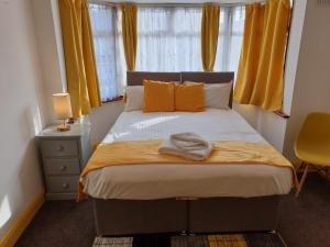 - une chambre avec un grand lit et des rideaux jaunes dans l'établissement Large 4bed house up to 7beds parking Slough Train Station, à Slough
