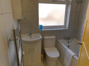 a bathroom with a toilet and a sink and a window at Large 4bed house up to 7beds parking Slough Train Station in Slough