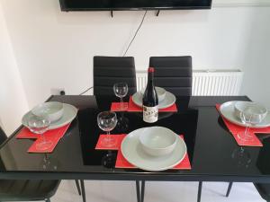 een zwarte tafel met glazen en een fles wijn bij Large 4bed house up to 7beds parking Slough Train Station in Slough