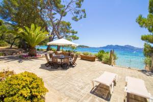 a patio with a table and chairs and the water at Villa Señorial primera linea de playa in Pollença