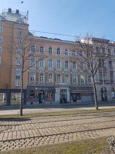 ein großes Backsteingebäude auf einer Straße mit zwei Bäumen in der Unterkunft Gerald`s Apartment 16 in Wien