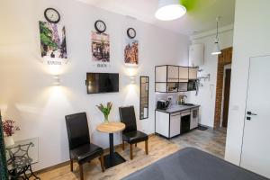 a living room with a table and chairs and a kitchen at Green - Apartamenty Kleparskie in Kraków