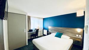 a hotel room with a white bed and a blue wall at Hôtel Restaurant Kyriad de Péronne in Péronne