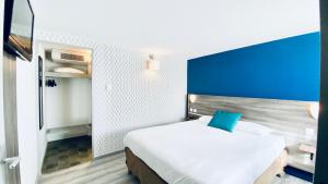 a bedroom with a large bed with a blue headboard at Hôtel Restaurant Kyriad de Péronne in Péronne