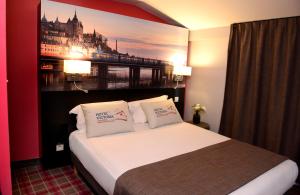 a hotel room with a bed with a picture on the wall at Hotel Victoria Lyon Perrache Confluence in Lyon