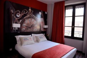 a bedroom with a bed with a large clock on the wall at Hotel Victoria Lyon Perrache Confluence in Lyon