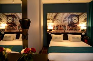 two beds in a room with clocks on the wall at Hotel Victoria Lyon Perrache Confluence in Lyon