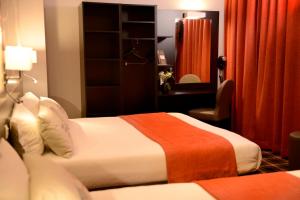 a hotel room with two beds and a chair at Hotel Victoria Lyon Perrache Confluence in Lyon