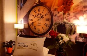 eine Uhr, die an einer Wand neben einem Kissen hängt in der Unterkunft Hotel Victoria Lyon Perrache Confluence in Lyon