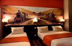 two beds in a hotel room with a mural of trains at Hotel Victoria Lyon Perrache Confluence in Lyon