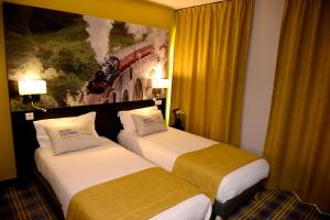 two beds in a hotel room with a painting on the wall at Hotel Victoria Lyon Perrache Confluence in Lyon
