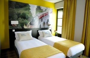 two beds in a hotel room with a painting on the wall at Hotel Victoria Lyon Perrache Confluence in Lyon