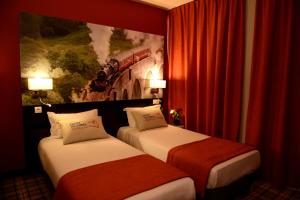 a hotel room with two beds and a painting on the wall at Hotel Victoria Lyon Perrache Confluence in Lyon
