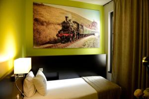 a painting of a train on a wall above a bed at Hotel Victoria Lyon Perrache Confluence in Lyon