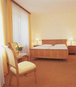 a bedroom with a bed and a chair and a table at Hotel An Der Wien in Vienna