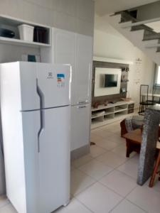a kitchen with a white refrigerator and a tv at Lindo sobrado a 100 m praia do Aruan. in Caraguatatuba